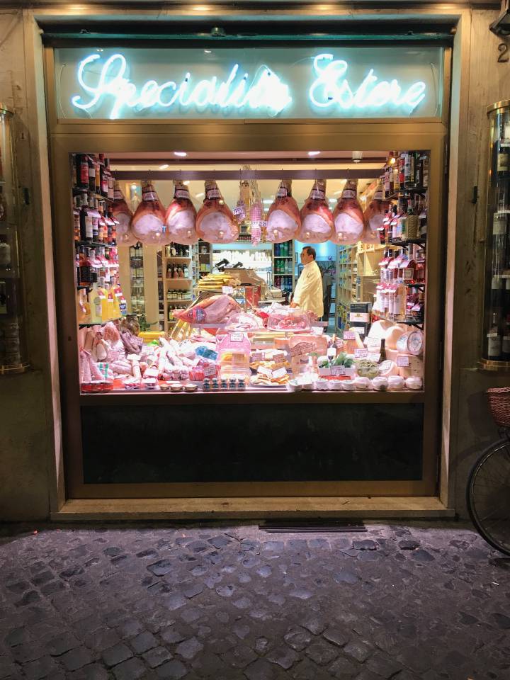 Ham hanging from the ceiling in the window of a butcher shop in Rome